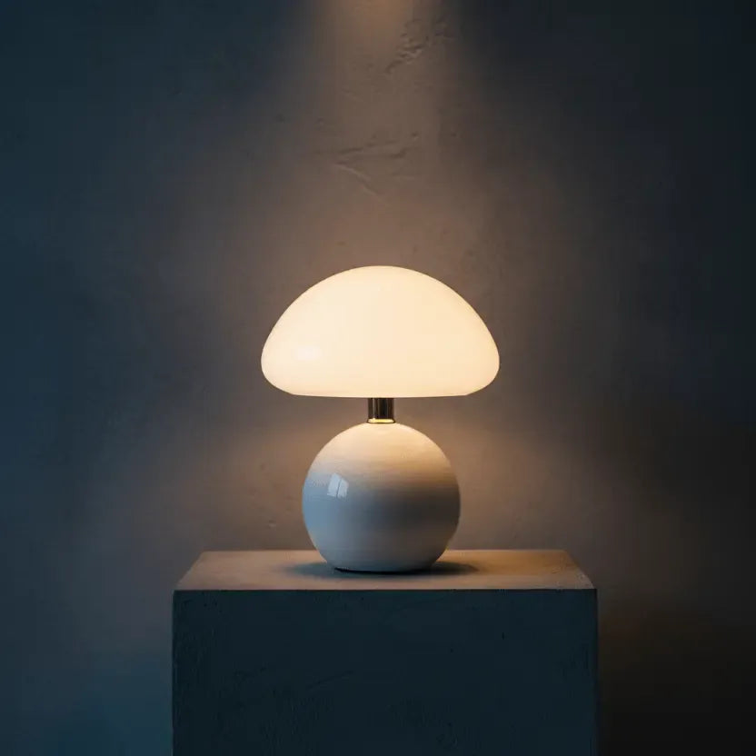 Lampe champignon design blanche éclairant un socle béton, lumière LED chaleureuse dans ambiance contemporaine.