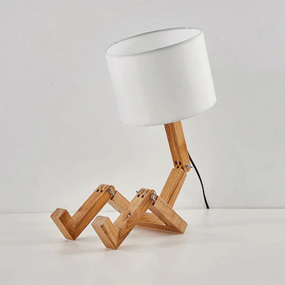 Lampe de bureau en bois avec bras articulé et câble visible, structure en bois naturel et abat-jour blanc sur fond neutre.