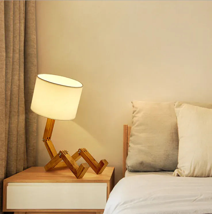 Lampe de bureau en bois placée près d’un lit, éclairage chaleureux parfait pour une ambiance reposante.