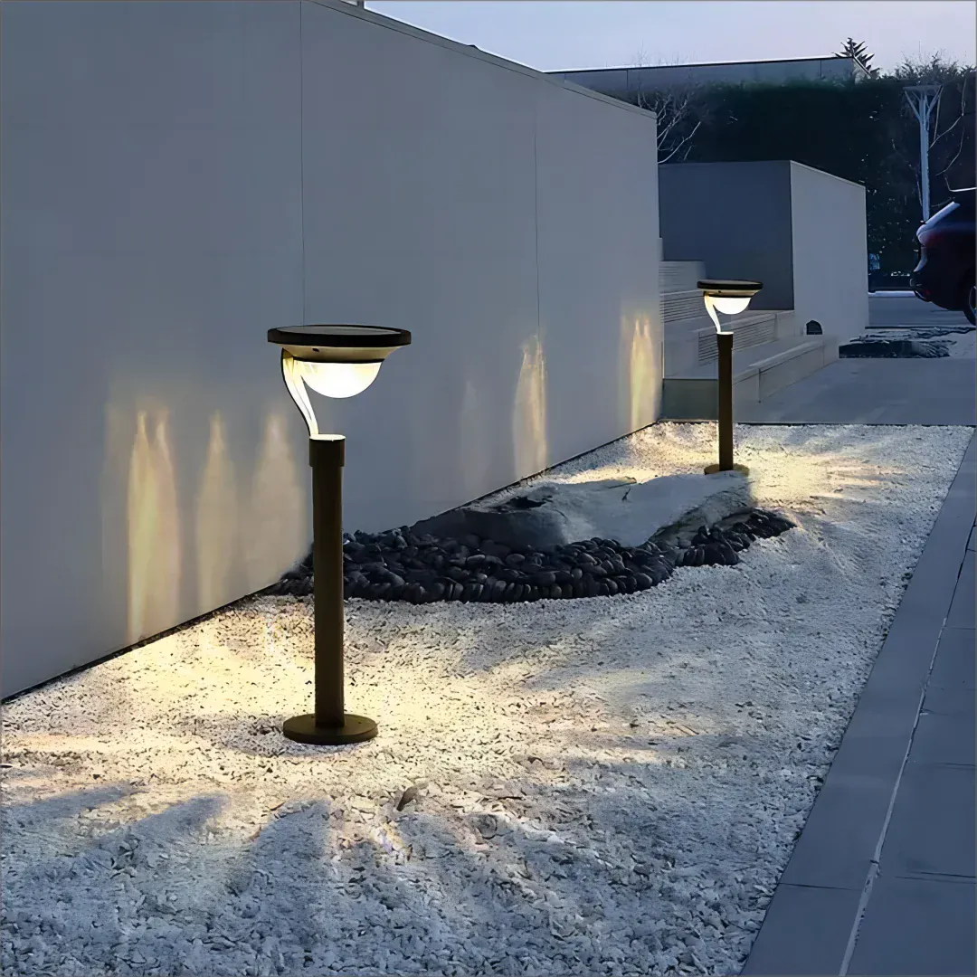 Lampe solaire extérieur sur pied moderne installée sur gravier le long d’un mur