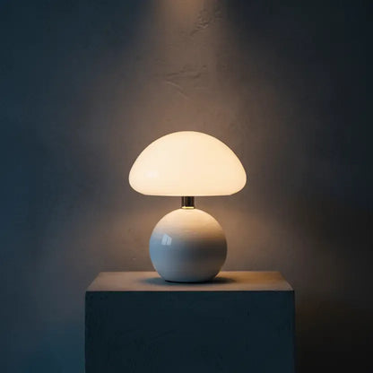 Lampe champignon design blanche éclairant un socle béton, lumière LED chaleureuse dans ambiance contemporaine.