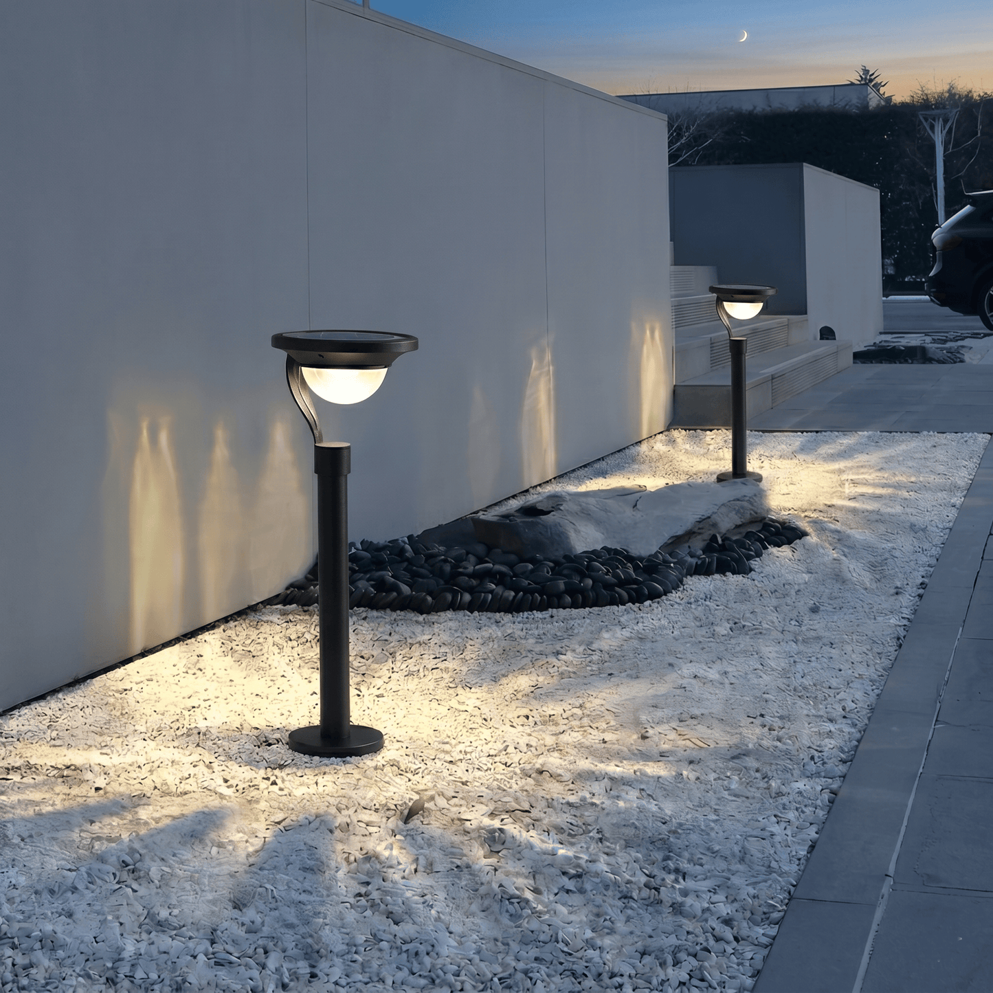 Lampe solaire extérieur sur pied moderne installée sur gravier le long d’un mur