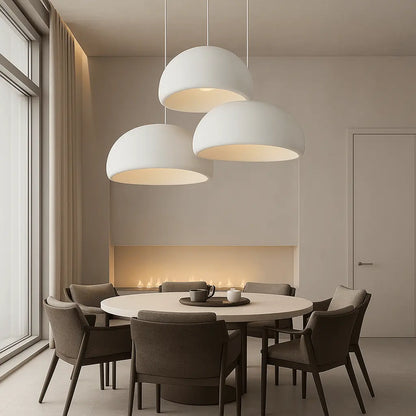 Trois suspensions design au-dessus d’une grande table, luminaire idéal pour salle à manger moderne.